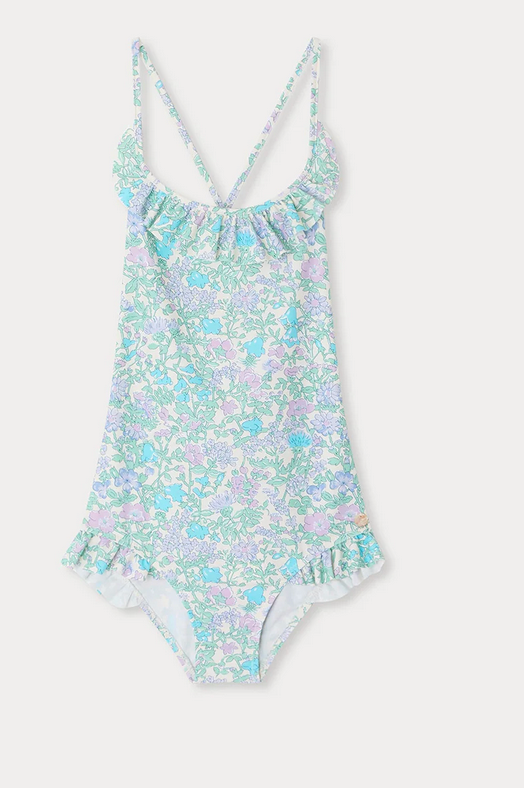 The Bonpoint Girls' Lacy One Piece Swimsuit features a Liberty fabric in light blue, pink, and lavender floral print with a ruffled neckline and crisscross spaghetti straps, shown on a white background.