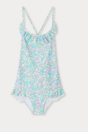 The Bonpoint Girls' Lacy One Piece Swimsuit features a Liberty fabric in light blue, pink, and lavender floral print with a ruffled neckline and crisscross spaghetti straps, shown on a white background.