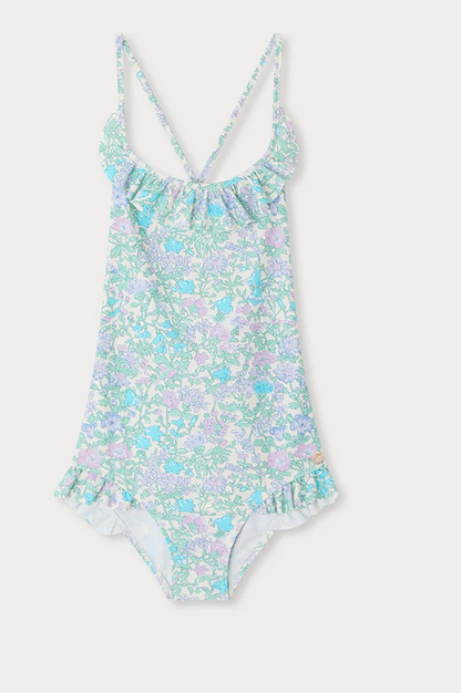 The Bonpoint Girls' Lacy One Piece Swimsuit features a Liberty fabric in light blue, pink, and lavender floral print with a ruffled neckline and crisscross spaghetti straps, shown on a white background.