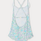 The Bonpoint Girls' Lacy One Piece Swimsuit is crafted from Liberty fabric, features crossed adjustable straps and an open back, and comes in pastel blue, green, and purple floral tones.