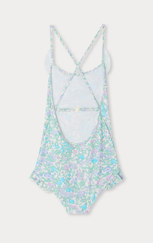 The Bonpoint Girls' Lacy One Piece Swimsuit is crafted from Liberty fabric, features crossed adjustable straps and an open back, and comes in pastel blue, green, and purple floral tones.