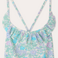 Close-up of Bonpoint's Girls' Lacy One Piece Swimsuit with a floral print in pastel purple, blue, and green, featuring thin shoulder straps and a ruffled neckline crafted from Liberty fabric.