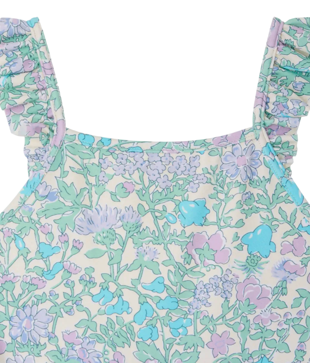 Close-up of the Bonpoint Baby Girls' & Girls' Cecilia One Piece Swimsuit, a sleeveless style with ruffled straps and a pastel floral pattern in purple, blue, and green.
