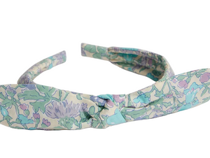 The Girls' Lorette Headband by Bonpoint features a stylish front knot and is crafted from pastel green, purple, and blue Liberty floral fabric.
