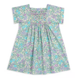 The Girls' Pais Smocked Dress by Bonpoint features short sleeves, a liberty floral print, and smocked detailing across the chest in soft pastel blue, green, and purple shades.
