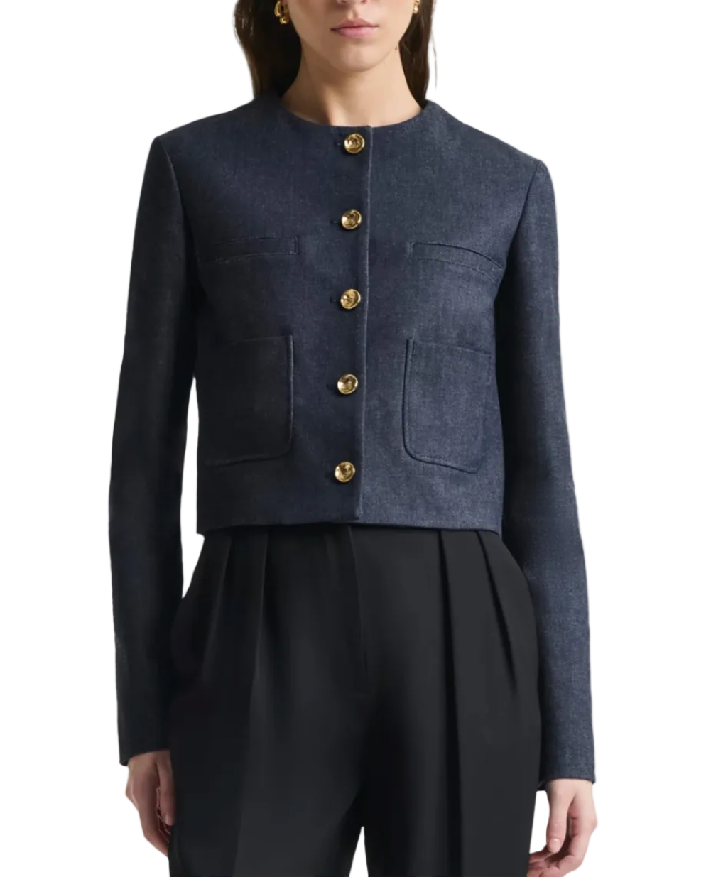A woman wears the Bernadette Jacket by Altuzarra—a navy blue, slim-fitting, collarless cropped jacket with four patch pockets and a button-up front—paired with black pleated trousers.