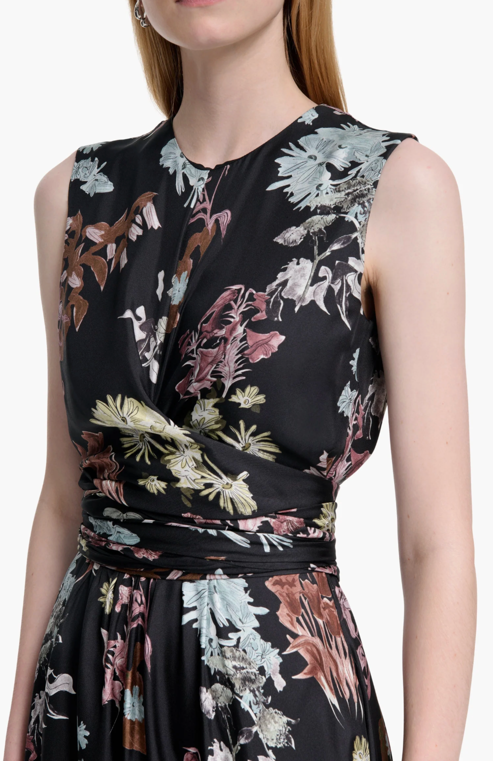 A woman wears the Altuzarra Penny Dress, a sleeveless black floral dress with a pastel print and gathered waist—perfect as a wedding guest outfit—shown from shoulders to waist.