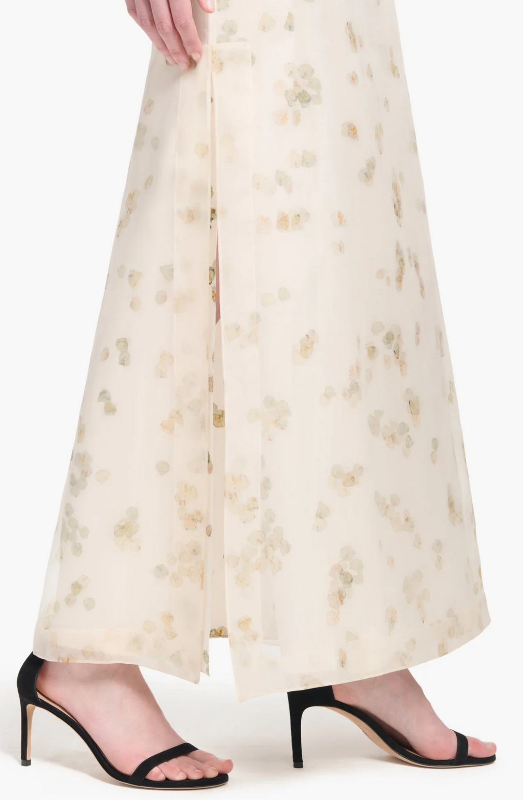 Someone in Altuzarra’s Linnie Skirt—a long, cream maxi with petal motifs and a side slit—pairs it stylishly with black high-heeled sandals.