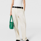 A person in a white sleeveless top, black sandals, holding a green woven handbag and wearing Stella McCartney Washed Cotton Straight Trousers—an effortlessly polished look with versatile tailoring.