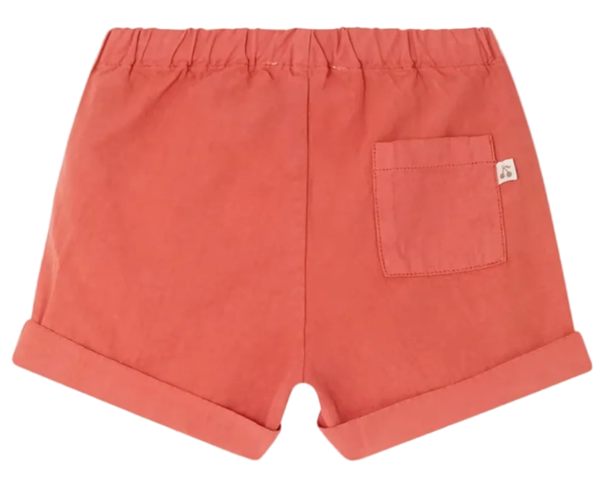 The Baby Boys' and Boys' Ecady Short by Bonpoint, in coral organic cotton, features an elastic waistband, rolled hems, and a right back pocket, shown from the back.