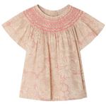 The Bonpoint Girls' Adelice Blouse features short sleeves, cream Liberty fabric with a pink floral pattern, and hand-embroidered smocked detailing at the neckline.