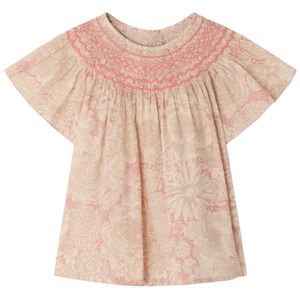 The Bonpoint Girls' Adelice Blouse features short sleeves, cream Liberty fabric with a pink floral pattern, and hand-embroidered smocked detailing at the neckline.
