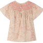 The Girls' Adelice Blouse by Bonpoint features short sleeves, a floral Liberty fabric, pink hand-embroidered smocking on the yoke, back button closure, and a light beige and pink palette.
