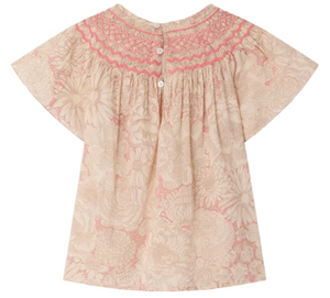 The Girls' Adelice Blouse by Bonpoint features short sleeves, a floral Liberty fabric, pink hand-embroidered smocking on the yoke, back button closure, and a light beige and pink palette.