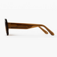 Side view of Jimmy Fairly Cinnamon eyeglass frames in brown cellulose acetate, featuring thick arms, a sturdy metal hinge, and clear lenses in an elegant oval shape, set against a plain white background.