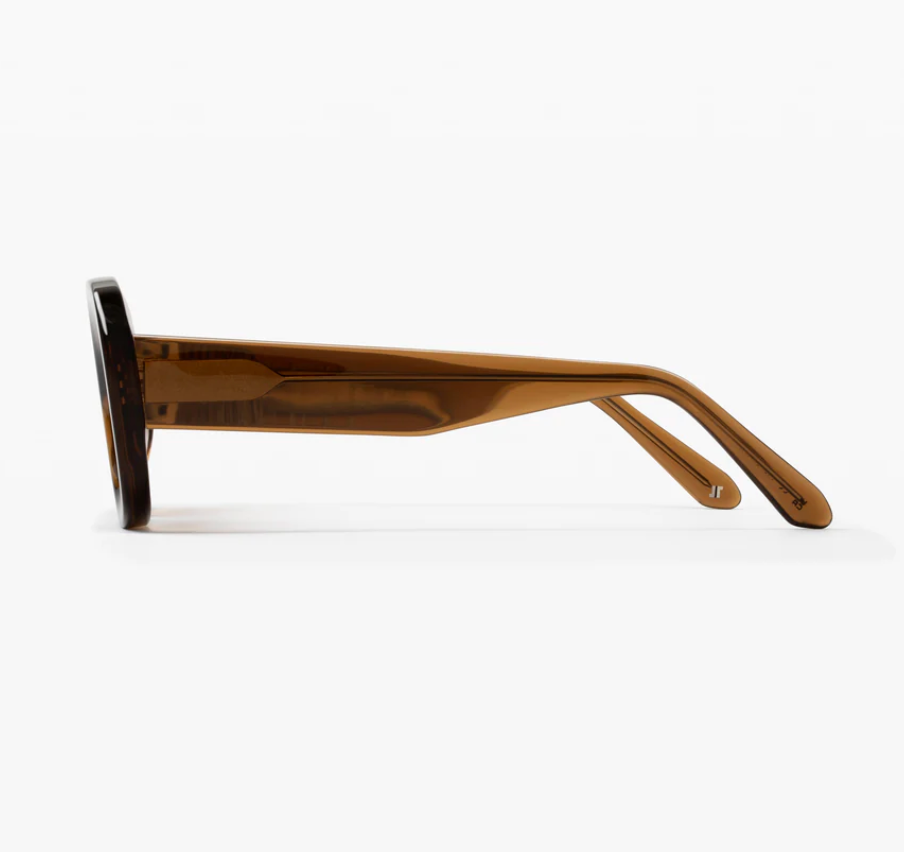 Side view of Jimmy Fairly Cinnamon eyeglass frames in brown cellulose acetate, featuring thick arms, a sturdy metal hinge, and clear lenses in an elegant oval shape, set against a plain white background.