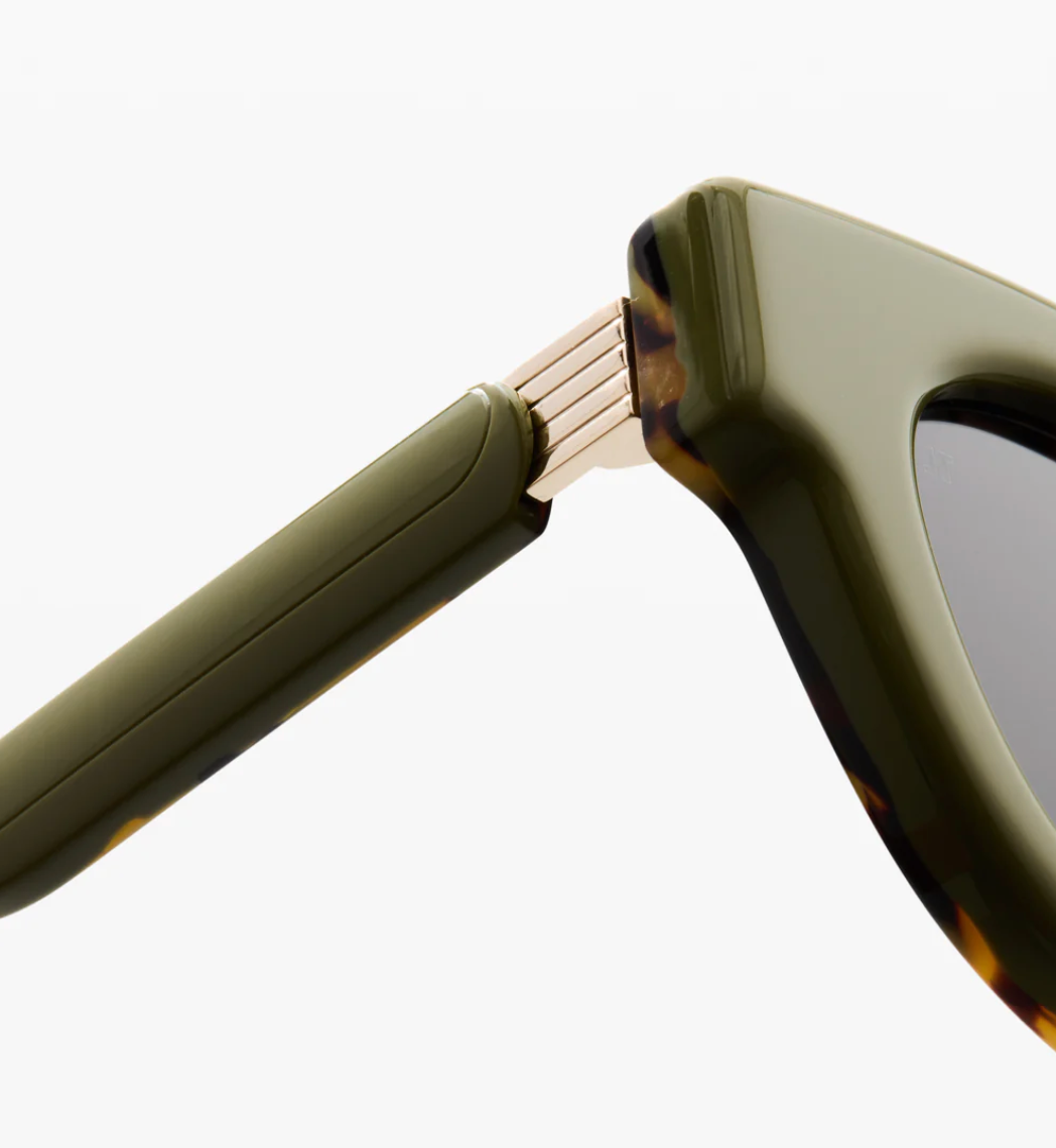 Close-up of the hinge and arm of Jimmy Fairly’s Paoli sunglasses, featuring a butterfly frame in green and tortoiseshell with gold metal detailing, expertly crafted from premium cellulose acetate.