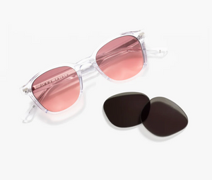Jimmy Fairly’s Adrian sunglasses, featuring clear frames with pink lenses and a sturdy 5-point metal hinge, are displayed next to two black replacement lenses on a white background.