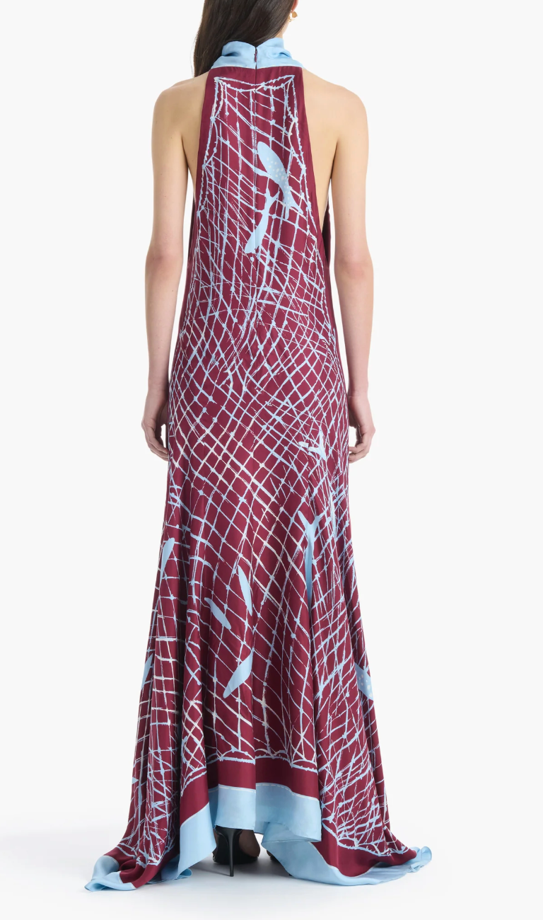 A person wearing the Altuzarra Moonlight Dress—a sleeveless, maroon silk dress featuring a high neckline and light blue abstract lines and patterns—stands with their back to the camera.