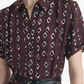 Wearing the Altuzarra Kiera Dress, a maroon short-sleeve piece featuring an elegant A-line silhouette, a geometric diamond pattern, and complemented by a thin black belt.