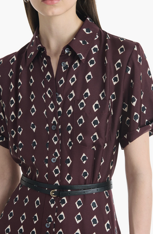 Wearing the Altuzarra Kiera Dress, a maroon short-sleeve piece featuring an elegant A-line silhouette, a geometric diamond pattern, and complemented by a thin black belt.