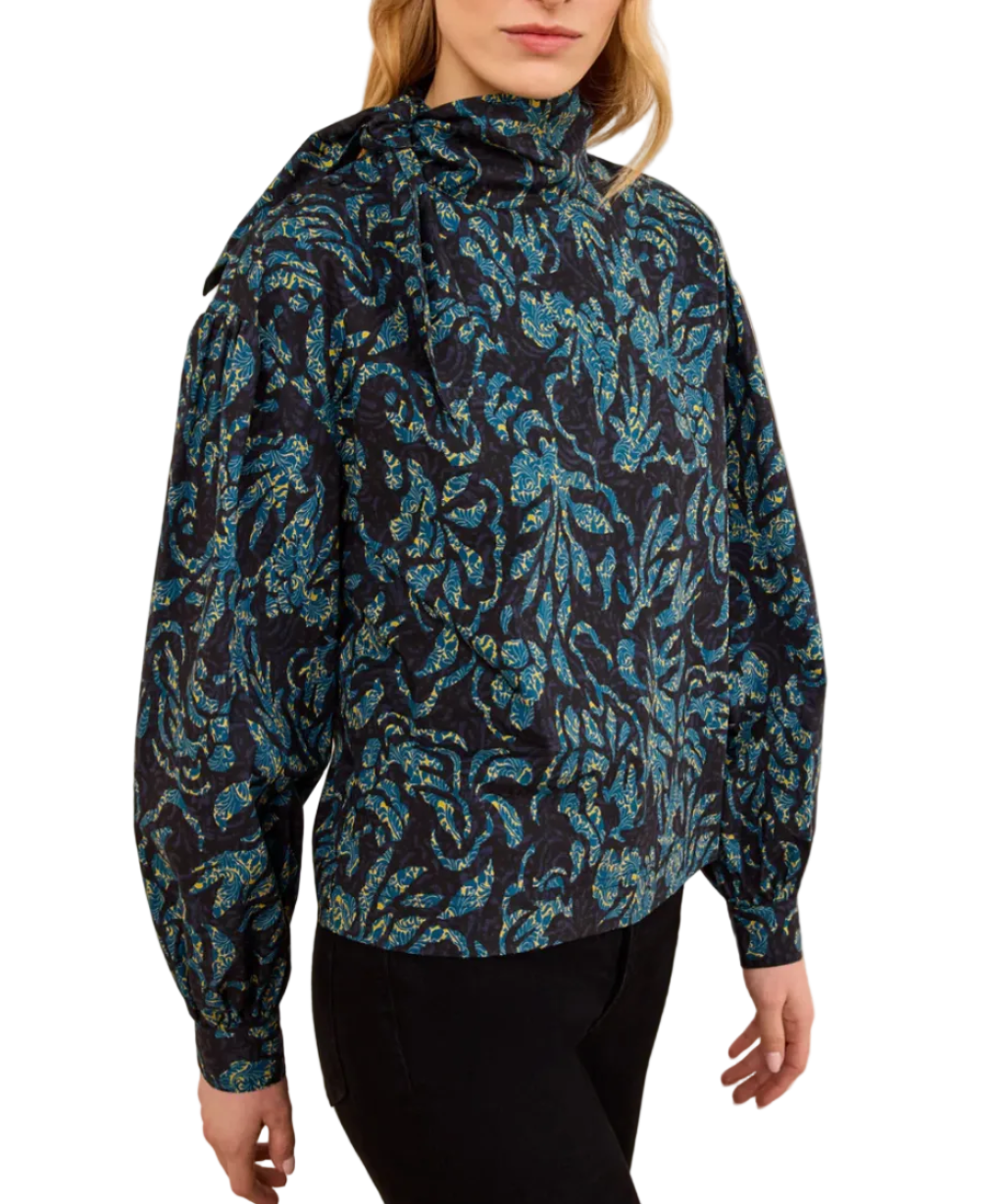 A person wearing the Ulla Johnson Pastel Long Sleeve Cotton Blouse, which features a structured silhouette with long sleeves and a high neck, paired with black pants and facing slightly to the side.
