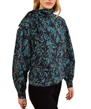 A person wearing the Ulla Johnson Pastel Long Sleeve Cotton Blouse, which features a structured silhouette with long sleeves and a high neck, paired with black pants and facing slightly to the side.