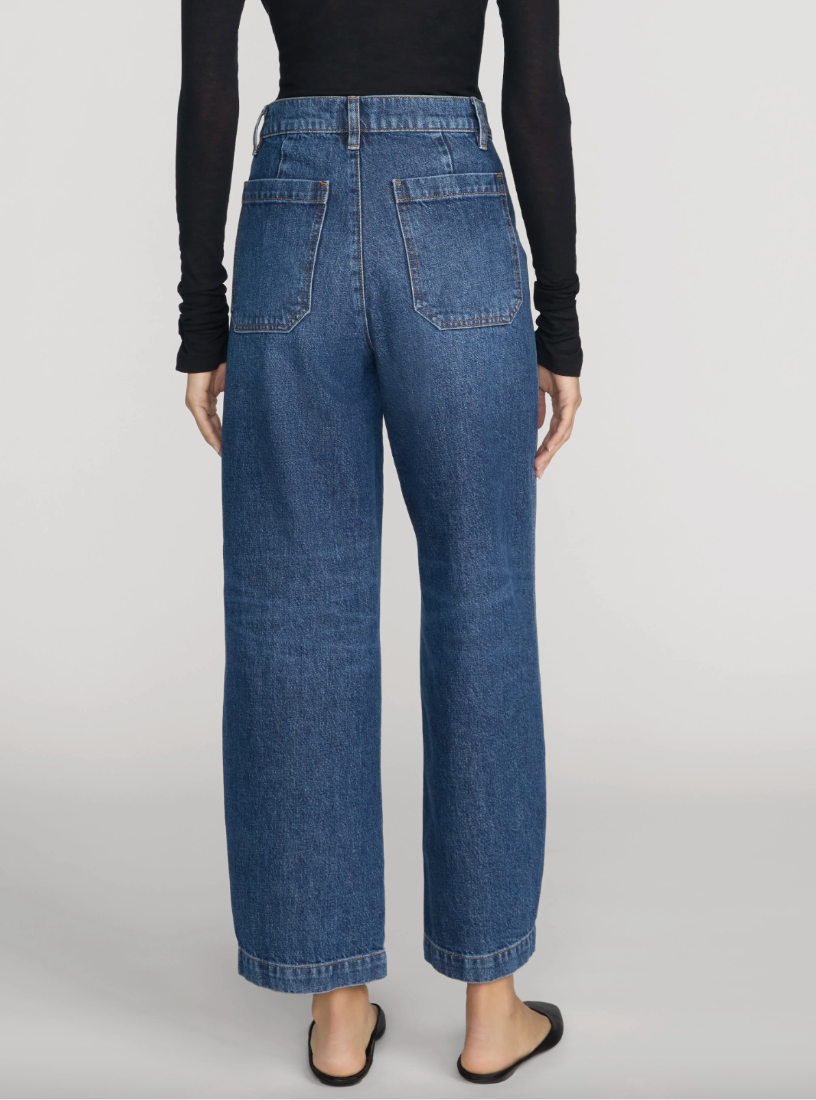 Model wearing The Ranger Pant by Frame—a high-waisted, wide-leg blue jean with a utility pocket—paired with a black long-sleeve top, photographed from the back against a plain background.