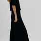A person wearing a black short-sleeved top and Suzie Kondi Megalo Velour Pants, featuring a wide-leg flared silhouette and front seam.