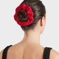 A woman with dark hair in a bun, secured by the Hunza G Scrunchie, wears a black sleeveless textured top and is shown from the back against a plain background.