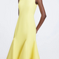 A person wears the Emilia Wickstead Seema Dress, a fitted yellow wool midi dress with a flared hem, standing against a plain background.