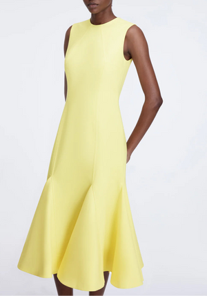 A person wears the Emilia Wickstead Seema Dress, a fitted yellow wool midi dress with a flared hem, standing against a plain background.