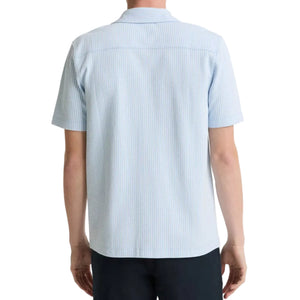 A person is seen from the back against a white background, wearing the vince Seersucker Stripe Shortsleeve Cabana Shirt in light blue and dark pants.