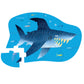 The Shark City 12 Piece Mini Puzzle by Crocodile Creek illustrates a travel-friendly shark jigsaw with a missing piece, surrounded by smaller fish on a blue background, perfect for enhancing hand-eye coordination.