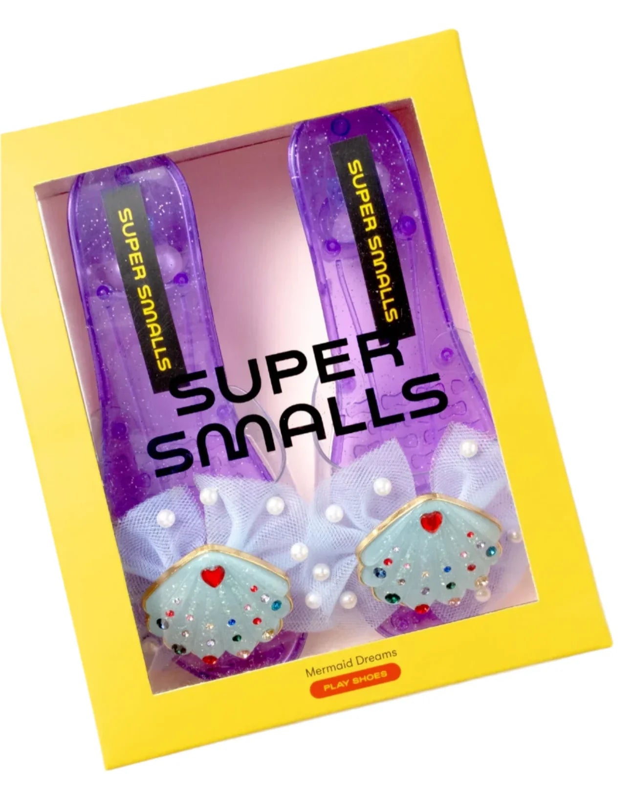 A pair of purple Super Smalls Mermaid Dreams Play Shoes for kids, featuring shell and heart designs, packaged in a yellow box.