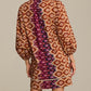 A woman is seen from the back wearing the Figue Hailey Dress—a relaxed fit, long-sleeve, knee-length style featuring geometric and ikat patterns in brown, orange, and purple.