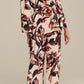 A woman faces away, wearing the Figue Avery Top—a loose, long-sleeve viscose crepe shirt with an abstract multicolor floral print—paired with flat sandals.