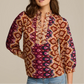 A woman wears the Figue Danilia Top, featuring a relaxed fit, notch collar, and ruffle trim, paired with light blue jeans.