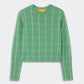 The Shrunken Checker Crew by Guest in Residence is a green women’s long-sleeve cashmere sweater with a white grid pattern, finished with ribbed cuffs and hem, shown against a plain white background.