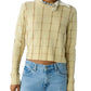 A cropped, pale yellow Shrunken Checker Crew cashmere sweater with a brown grid pattern and a white patterned neckerchief, worn with light-wash jeans.