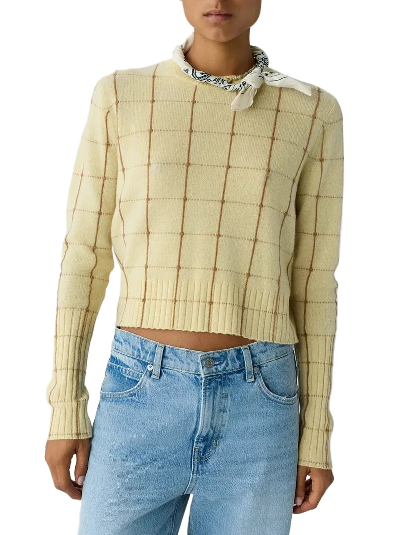 A cropped, pale yellow Shrunken Checker Crew cashmere sweater with a brown grid pattern and a white patterned neckerchief, worn with light-wash jeans.