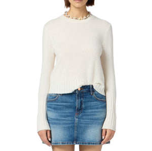 A person wears the Guest in Residence Shrunken Crew Cashmere Sweater styled with a blue denim mini skirt, standing against a white background.