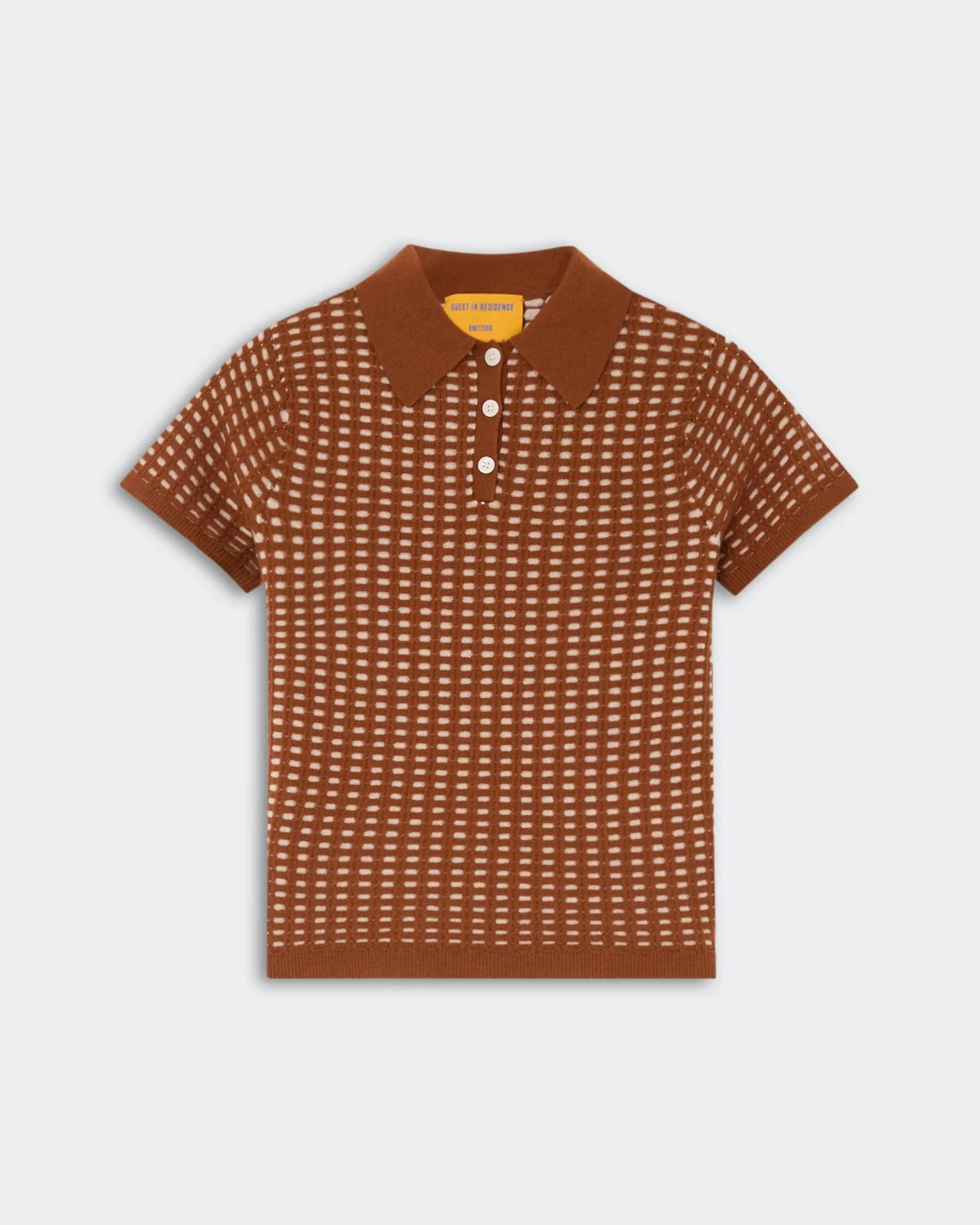 The Shrunken Waffle Polo by Guest in Residence is a brown, short-sleeve cashmere knit shirt featuring a white dotted pattern, button-up collar, ribbed edges, and a subtle waffle texture, shown against a plain light background.