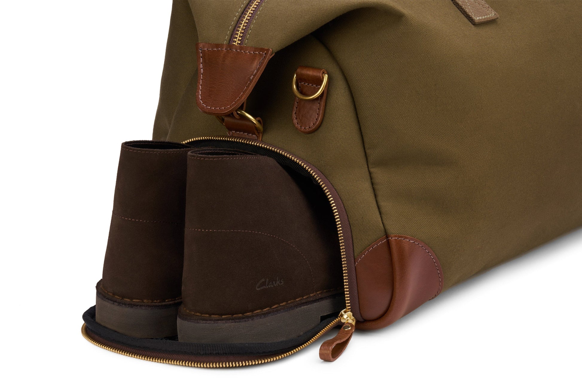 A pair of brown suede shoes nestled in a zippered compartment of the Bennett Winch Canvas Weekender, a green and brown full-grain leather-trimmed bag, perfect for stylish travel.