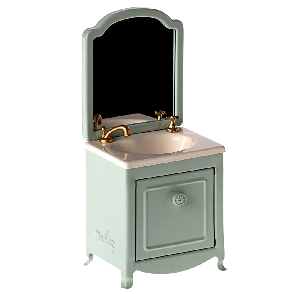 A small and elegant Maileg Sink Dresser for your mouse, featuring a mint green cabinet, a gold faucet, an attached mirror, and a cleverly hidden small closet under the sink.