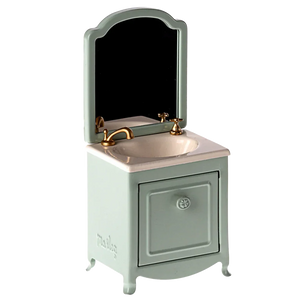 A small and elegant Maileg Sink Dresser for your mouse, featuring a mint green cabinet, a gold faucet, an attached mirror, and a cleverly hidden small closet under the sink.