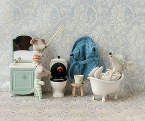 The Maileg Sink Dresser, Mouse - Mint by Maileg features a delightful miniature bathroom scene with toy mice: one relaxing in a bathtub, another fishing in a toilet, a third peering into a mirror at the sink, and a fourth wearing a bathrobe. The set includes various charming bathroom accessories and boasts a small closet under the sink for added storage.