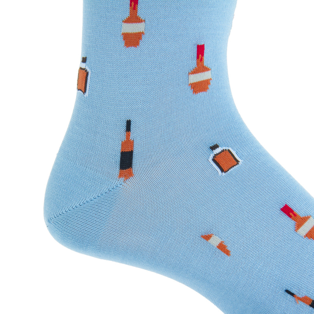 A close-up of a Dapper Classics Bourbon Bottles Mid Calf Socks in Sky Blue, made in USA and adorned with various bottles and glassware motifs.