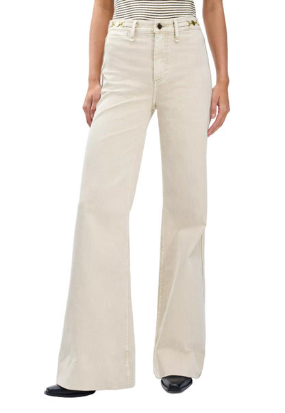 A person wears Rag & Bone Skylar High Rise Trouser Jeans in vintage stretch denim with a striped sleeveless top and black pointed shoes.