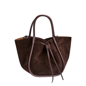 The Proenza Schouler Small Ruched Soft Suede Tote features a sculptural silhouette, two handles, and a drawstring closure. Photographed against a white background.